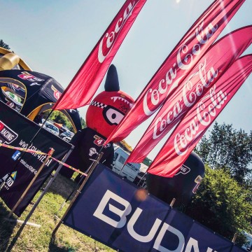 Advertising flags with the CocaCola brand during an automotive event.